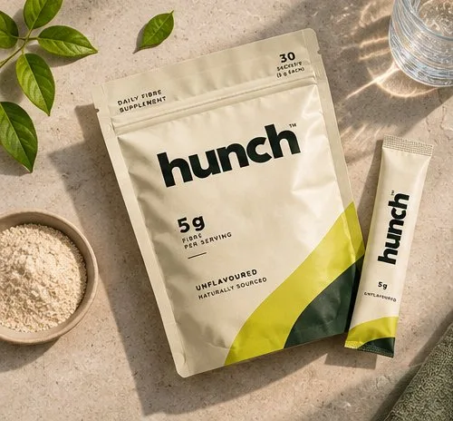 Top-down view of the hunch fiber pouch and stick pack next to a bowl of powder and a glass of water